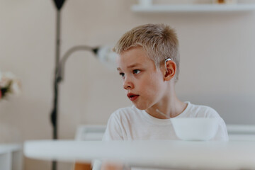 A boy with hearing aids enjoys a healthy breakfast, showcasing inclusive daily routines and...