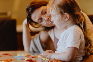 A sweet 3-year-old girl plays board games with her mom, sharing precious moments of love, learning...
