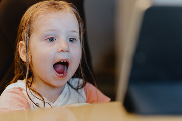 An expressive 3-year-old girl watches cartoons on a tablet, capturing genuine childhood reactions...