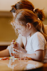 A sweet 3-year-old girl plays board games with her mom, sharing precious moments of love, learning...