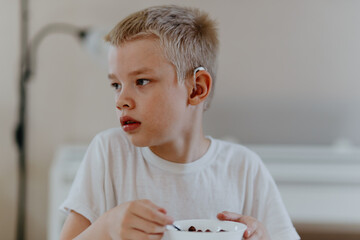 A boy with hearing aids enjoys a healthy breakfast, showcasing inclusive daily routines and...