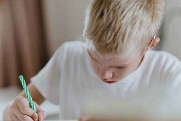 A boy with hearing aids focuses on homework, showcasing natural inclusive education. Authentic...