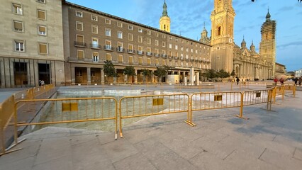 Vast sunlit square with golden barriers beside Gothic cathedral, evoking Andalusian siesta charm and el Dia de la Hispanidad reflections