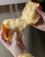 Gloved hands gently tear pillowy brioche bread, evoking buttery decadence ideal for Hanukkah feasts...