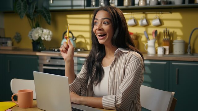Latina American woman ethnic girl student thinking online studying at home kitchen brainstorm create planning idea solution happy insight female teen freelancer businesswoman typing laptop computer