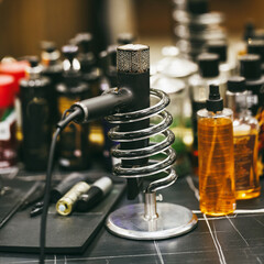 Hair dryer in a chrome spiral holder on a barber’s workstation, surrounded by grooming products...