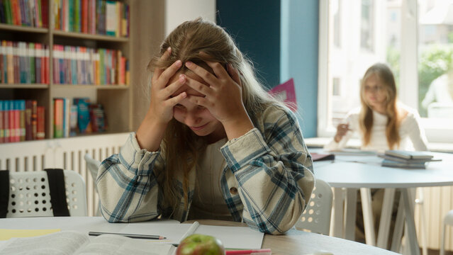Stressed angry Caucasian teen sad girl school student pupil kid child schoolgirl study exam task hard education difficult learning studying subject library book read problem exhausted tired overworked