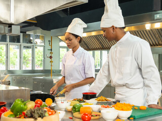 Chefs professional action demonstrating their stand cooking skills over high flame in commercial...