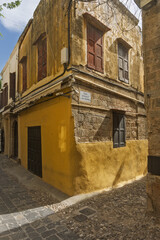 narrow alleyway paved with stone tiles and flanked by aged stone and stucco buildings stone arches span across the alley overhead in old town of Rhodes, Greece