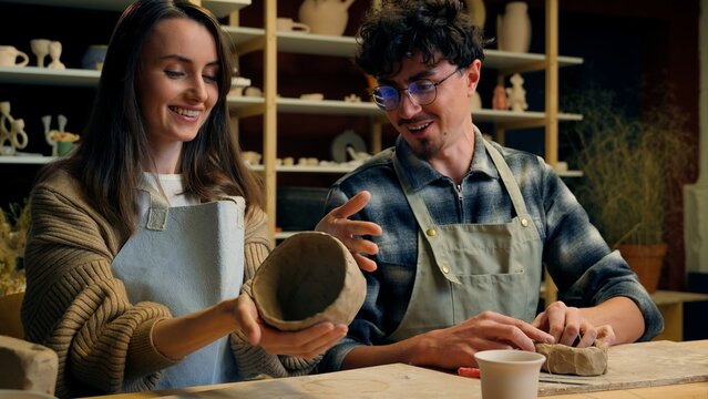 Caucasian family smiling girl guy couple date in pottery workshop handmade master class woman potter sculptor artist teaching student man modeling clay together hobby craft stoneware in art studio