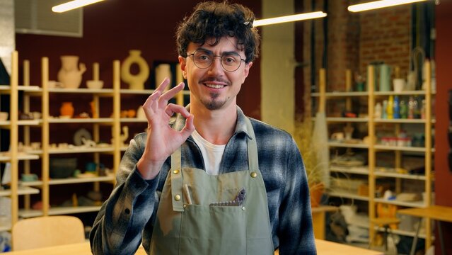 Caucasian man portrait smiling guy sculptor potter craftsman in pottery workshop designer artisan male small business owner craft shop art studio master handmade ceramics posing artist okay gesture