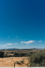 Expansive Blue Sky Over Dry Golden Landscape and Rolling Hills

