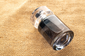 One bottle of perfume on jute cloth, close-up.