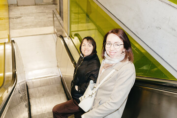 Portrait of two girls going down the escalator in the subway in the evening.