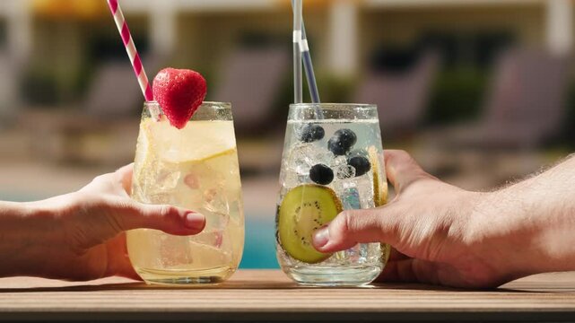 Fruit cocktail in hotel bar, Two cocktail glasses cheers in the hands on sea background. Bartenter making drink in bar, Summer vacation concept, A beautiful couple enjoy the vacation at the beach.