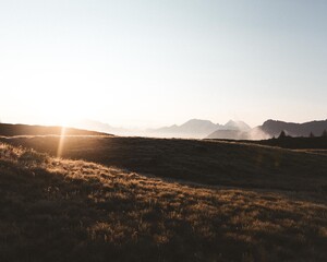 Sunrise mist over alpine meadow and silhouetted peaks beneath a clear, expansive sky