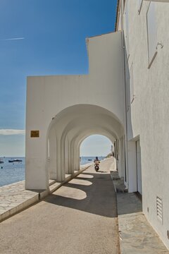 Empty narrow streets of Cadaqu&eacute;s, Spain, with one motorbike houses and clear blue sky. The peaceful historic town center is beautifully captured, highlighting its charm and tranquility.