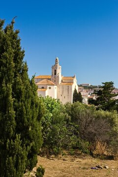 Charming narrow streets of Cadaqu&eacute;s, Spain, with white church on the hill, houses and vibrant blue sky, showcasing the historic Mediterranean coastal town&rsquo;s beauty and traditional architecture