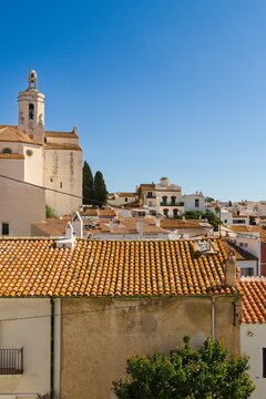 Charming narrow streets of Cadaqu&eacute;s, Spain, with white church on the hill, houses and vibrant blue sky, showcasing the historic Mediterranean coastal town&rsquo;s beauty and traditional architecture