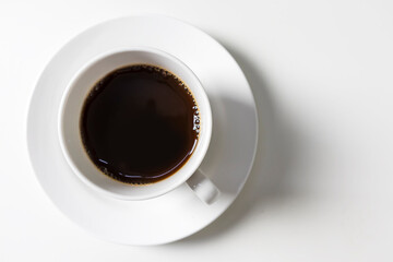 White cup and black coffee on white table in top view