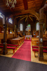 Empty wooden church interior with red carpet leading to altar with stained glass windows in...