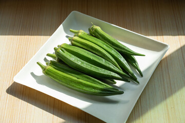 A plate of fresh okra on the table. Fresh seasonal ingredient. 