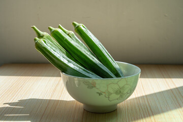 A plate of fresh okra in a bowl on the table. Fresh seasonal ingredient. 