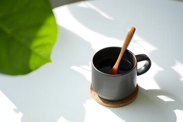Dark mug coffee wooden spoon green leaf shadows black