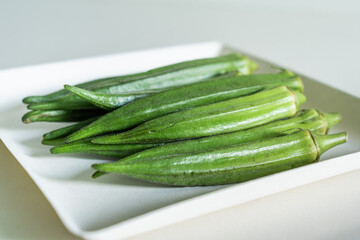 Okra. Fresh seasonal ingredient. Food photography on a plate on white background.






