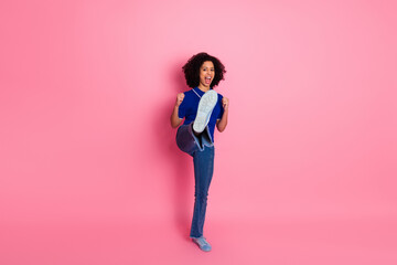 Young woman in casual blue attire expressing excitement with a joyful pose against a bright pink...