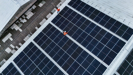 Solar power technician inspecting rooftop solar panels, performing maintenance and installation of...