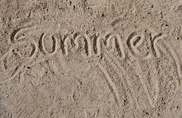 Summer written in sand on beach symbolizing vacation fun