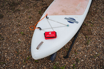 This paddle board for water sports includes a securely attached bright red first aid kit, enhancing...