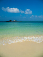 Serene tropical beach with crystal clear turquoise water, gentle waves, and a bright blue sky with fluffy white clouds. peaceful and relaxing summer scene perfect for panorama and travel concepts.