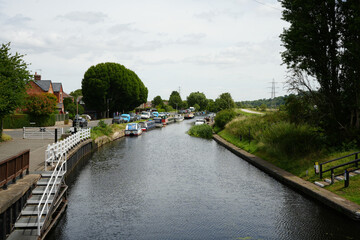 Nottingham, England - June 20 2025: Peaceful canal scene with moored boats, greenery, and locals in...