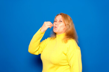 Caucasian woman in her 40s wearing a yellow sweater with a positive and happy smile showing a delicious perfect gourmet sign isolated over blue colored background