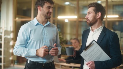 Caucasian men businessmen business partners friendly conversation dialogue talking in office coffee break drinking together guys male co-workers colleagues friends fellows meeting drink tea at company