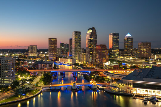 Night urban landscape of downtown district of Tampa in Florida, USA. American city skyline with brightly illuminated high commercial buildings and bridge over Hillsborough river.