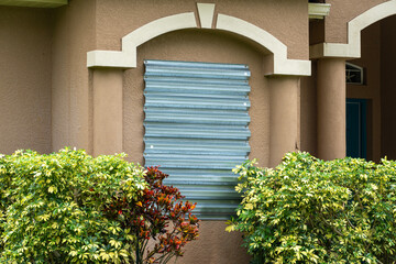 Storm resistant steel shutters cover windows of Florida house as precaution before hurricane. Home...