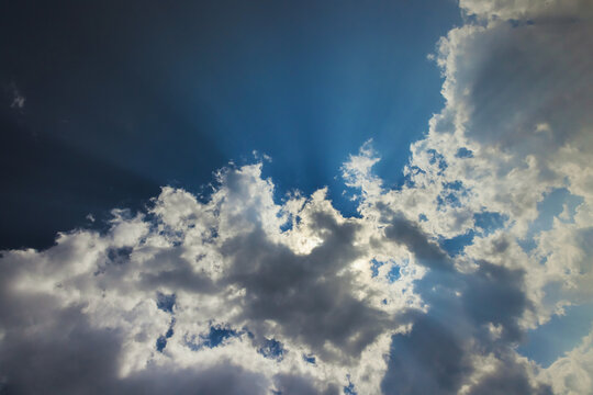 Soft clouds float in fluffy sky as sunlight streams through, creating serene atmosphere on sunny afternoon
