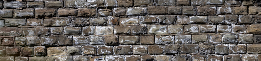 Old stone gray background with white sloppy spots. Stone blocks are laid out in rows. Panorama. Copy space.