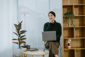 Beautiful Asian woman sitting working on laptop in office
