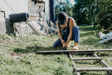 male builder restores old wooden house, replacing boards