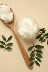 Shea butter and leaves on beige background, flat lay