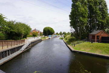Nottingham, Nottinghamshire / England - June 20 2025: A peaceful canal scene in a small village with narrowboats, greenery, and a red-brick 