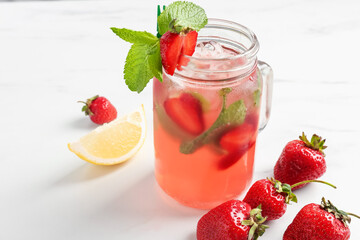 Refreshing drink with strawberries and mint on white table, closeup