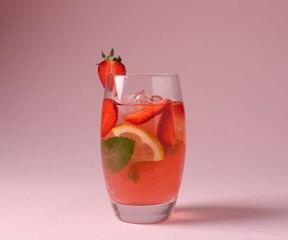 Refreshing drink with strawberries, mint, lemon and ice in glass on pink background, closeup