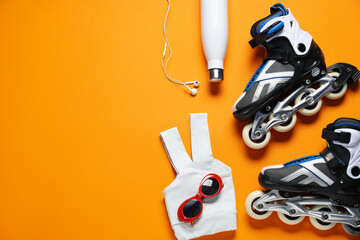 Flat lay composition with roller skates on orange background. Space for text