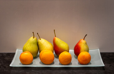 Apricots and pears on white glass tray