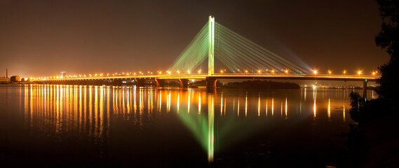 Kyiv at night, South Bridge on the Dnieper River, reflection of night lights on the water. Beautiful view background, quite waves surface. Europe architecture landscape.